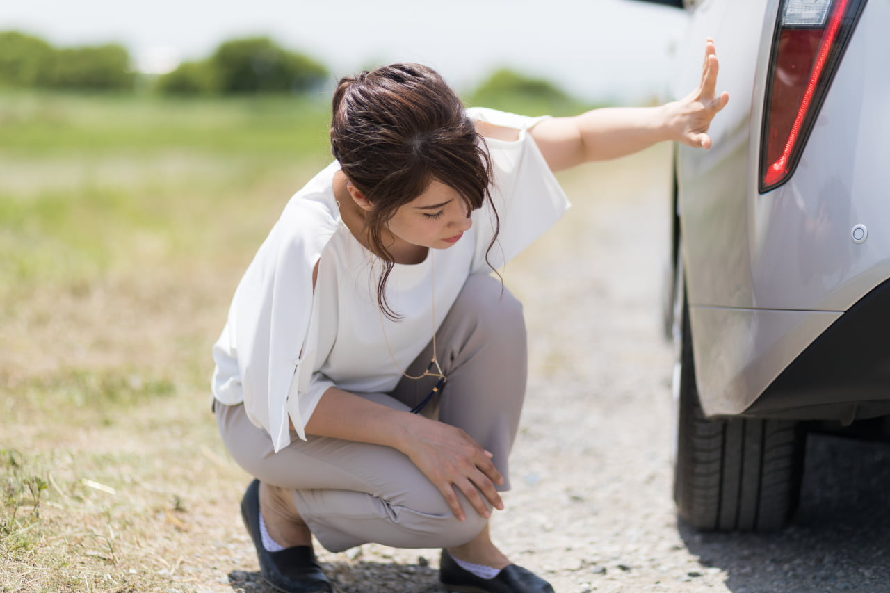 女性が車の下をみている様子